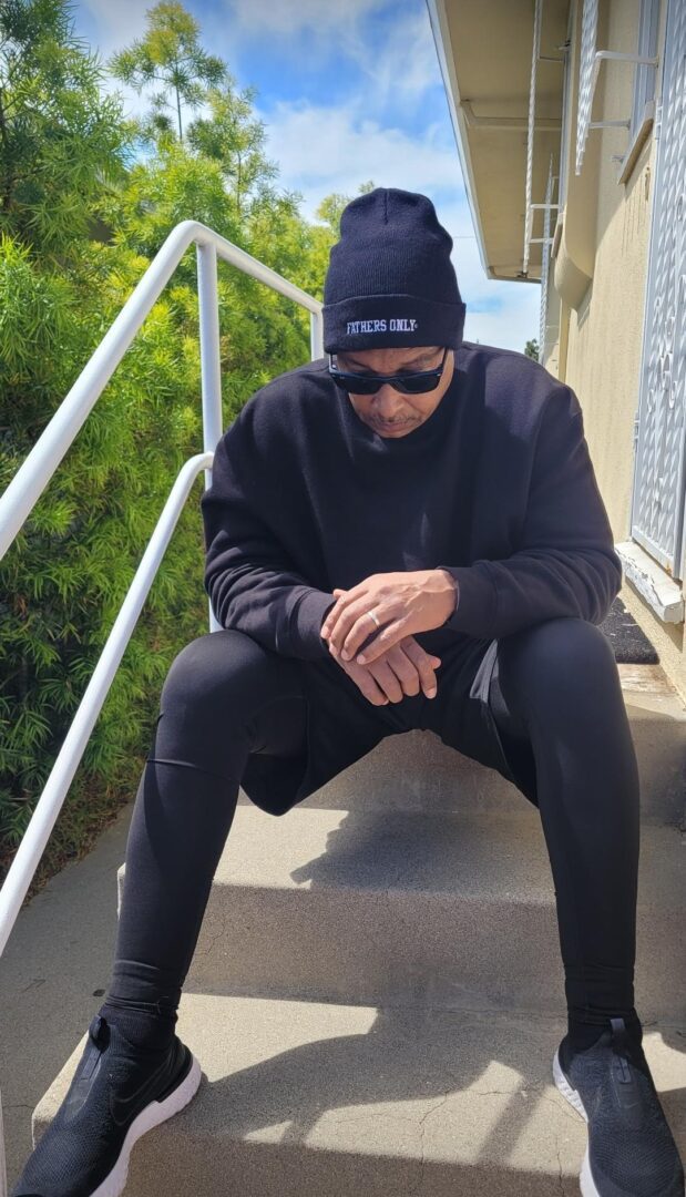 A man sitting on the steps of stairs wearing sunglasses.